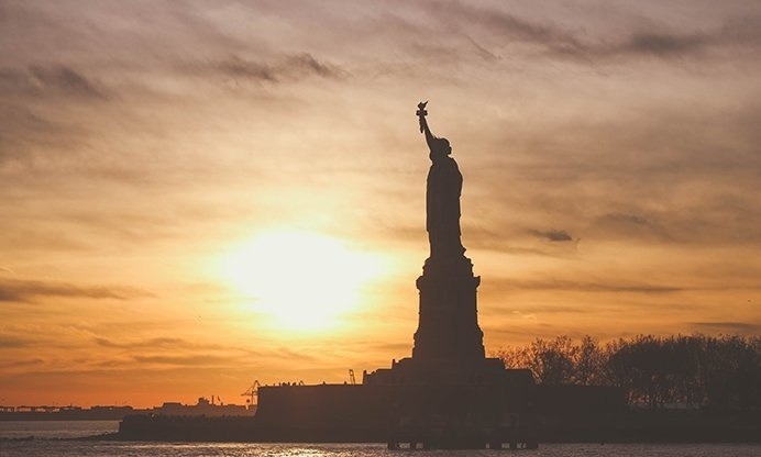 Photo of Statue of Liberty with sun setting in background